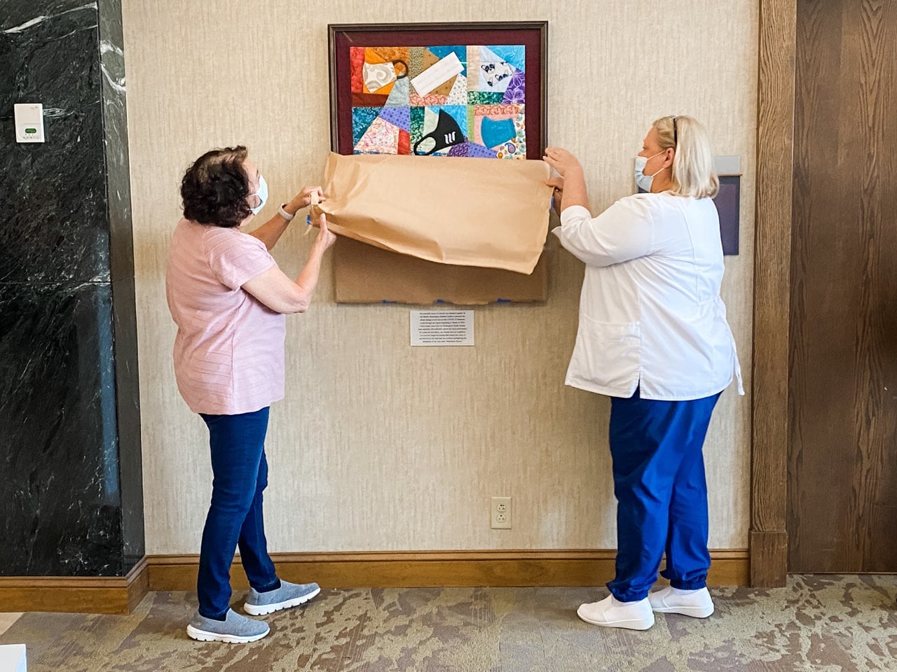 Photo of two employees revealing new artwork