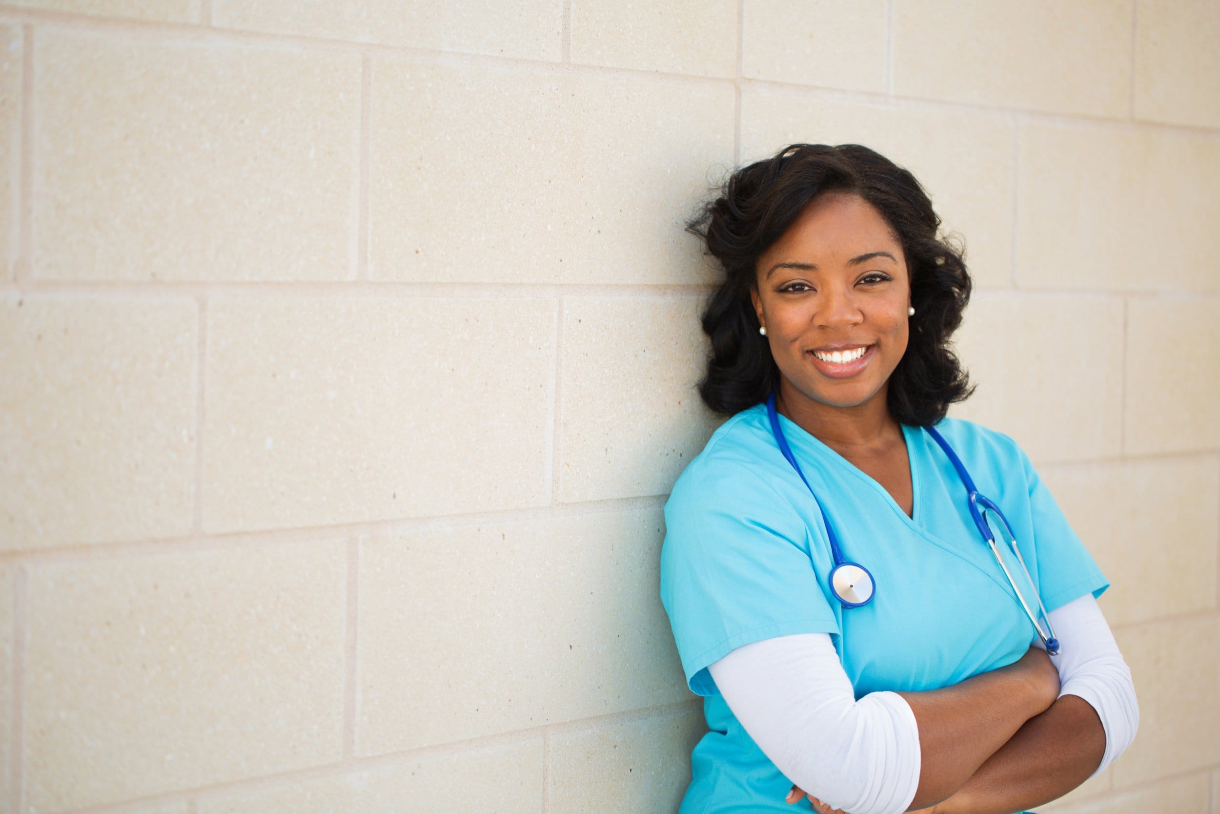 Healthcare worker in uniform standing near white wall
