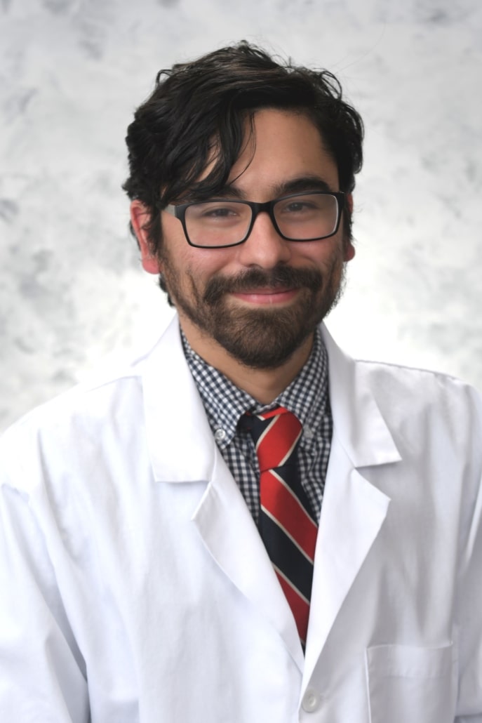 Dr. Alonso Diaz in a white lab coat, smiling.